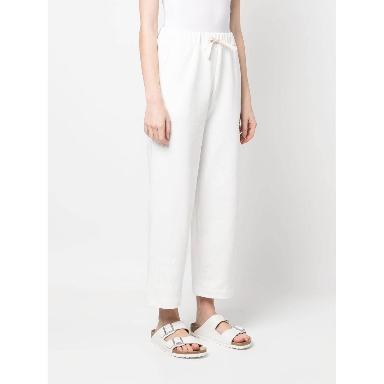 White cotton Joshua Sanders trousers with elasticated drawstring waistband and graphic print detail, shown on model.
