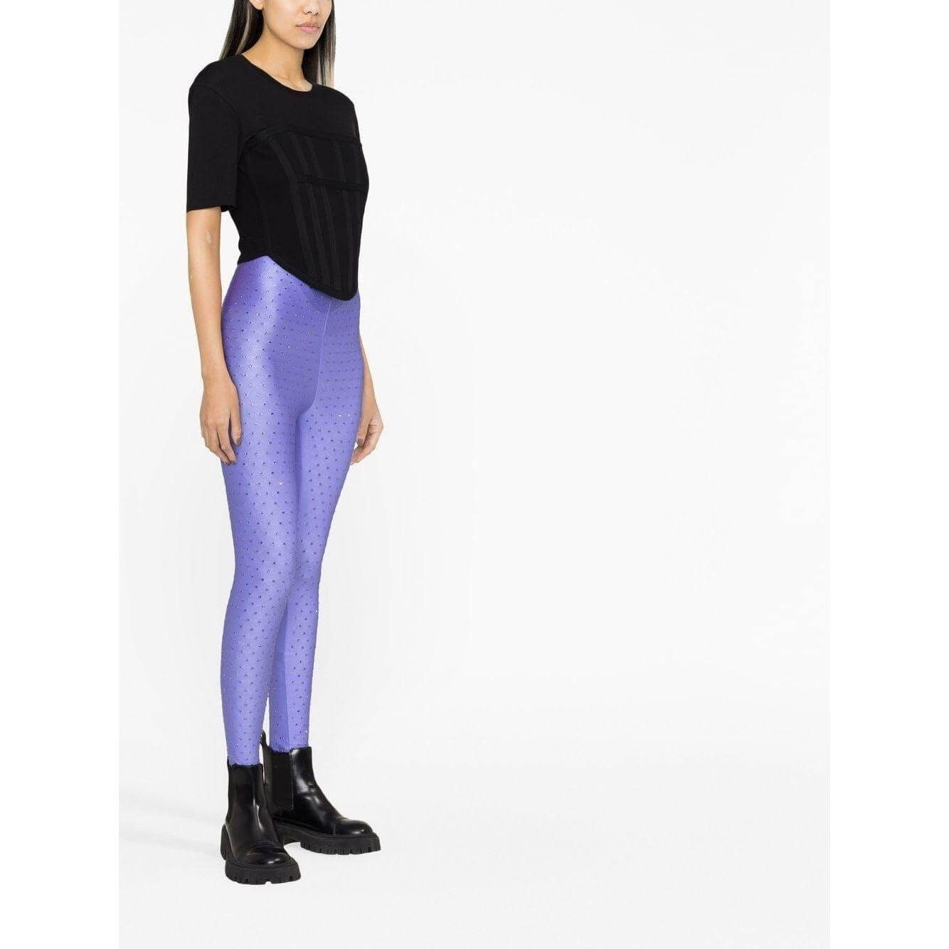Model wearing THE ANDAMANE lilac rhinestone embellished leggings, high-waisted, skinny cut, paired with black top and boots.