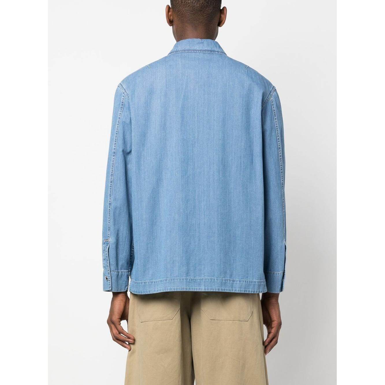 Back view of model wearing Lanvin zip-up denim shirt in light blue with long sleeves and classic collar, paired with beige pants.