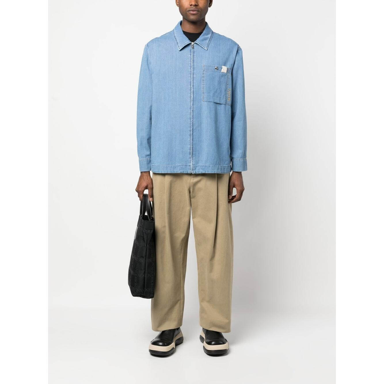 Lanvin clear blue zip-up denim shirt with classic collar and embroidered logo, worn by model holding a black bag.
