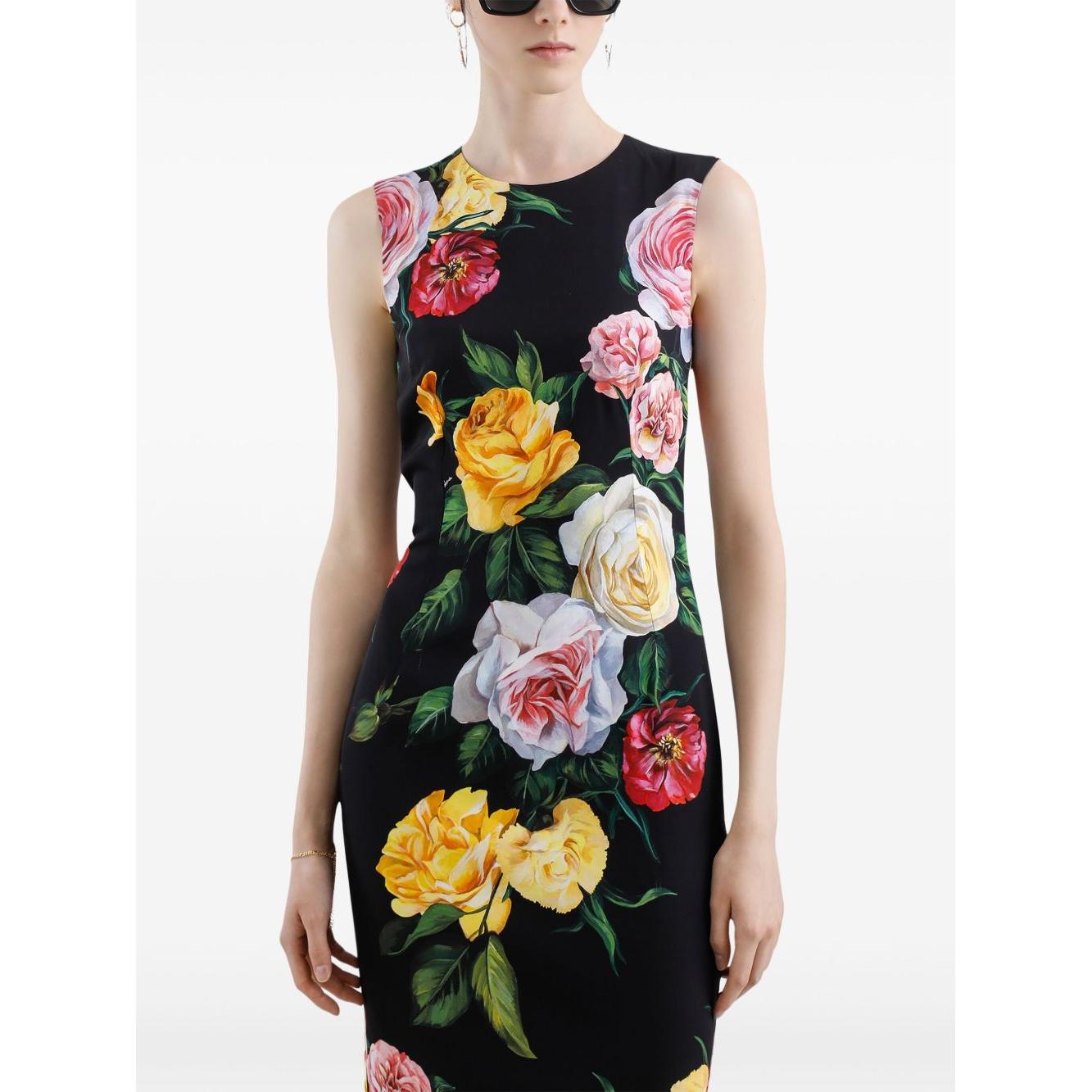 Model wearing black Dolce & Gabbana sleeveless floral print midi dress with vibrant rose pattern, round neck, and concealed rear fastening.
