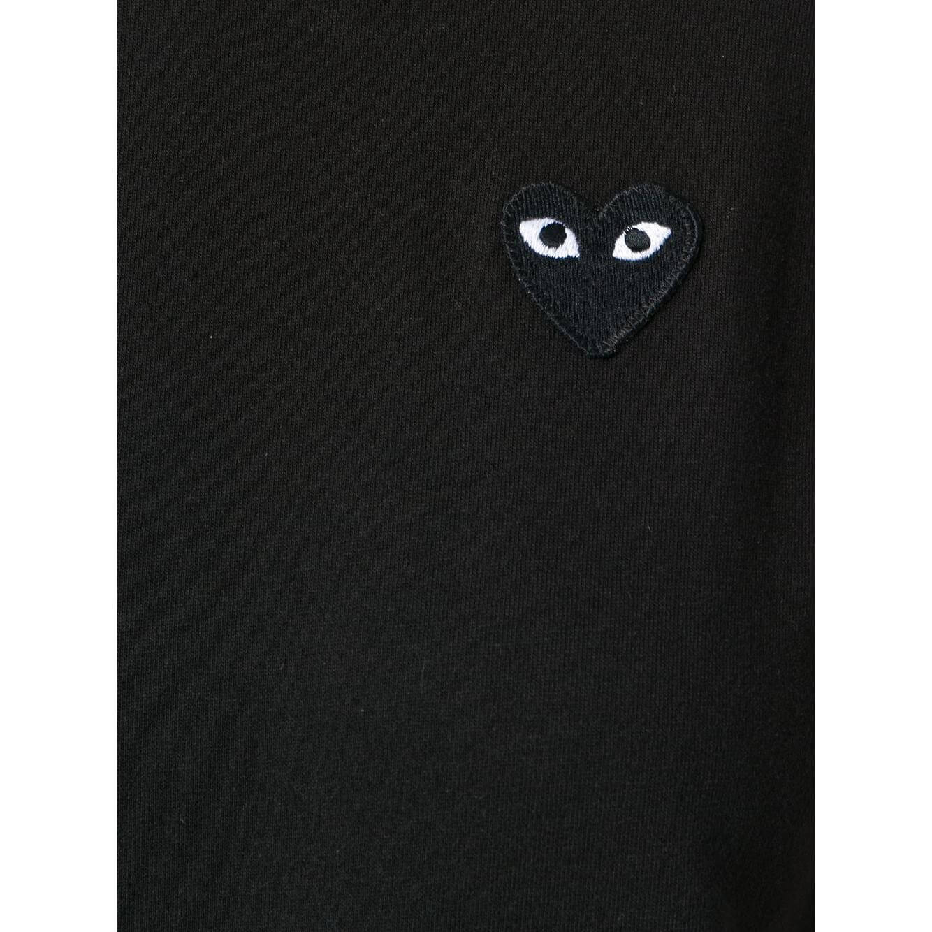Black Comme des Garcons T-shirt with almond-eyed heart logo on chest.