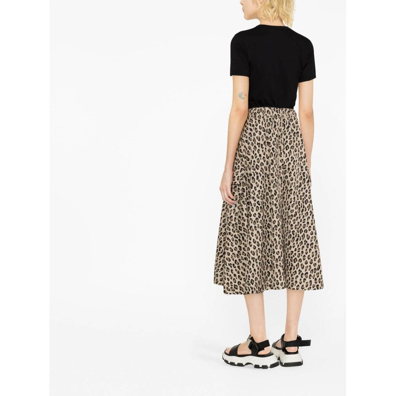Woman wearing a black t-shirt paired with a leopard print midi skirt and chunky sandals, viewed from the back.