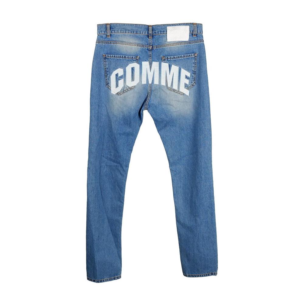 Back view of Comme Des Fuckdown blue denim men's jeans with bold white 'COMME' text across the pockets, showcasing unique stitch design.