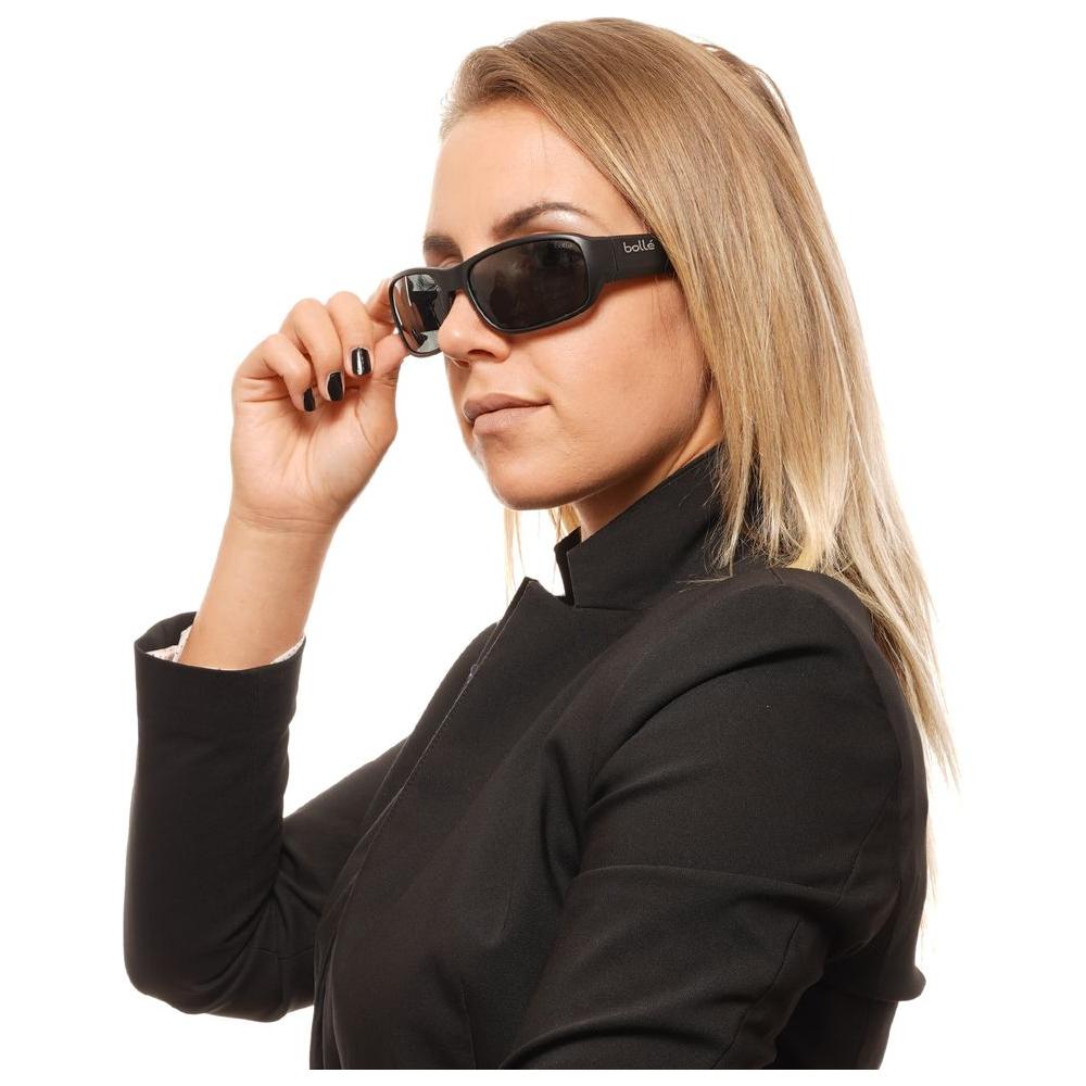 Person wearing Bolle Black Unisex Sunglasses with full-rim plastic frame and grey lenses, holding the frame for a stylish look.