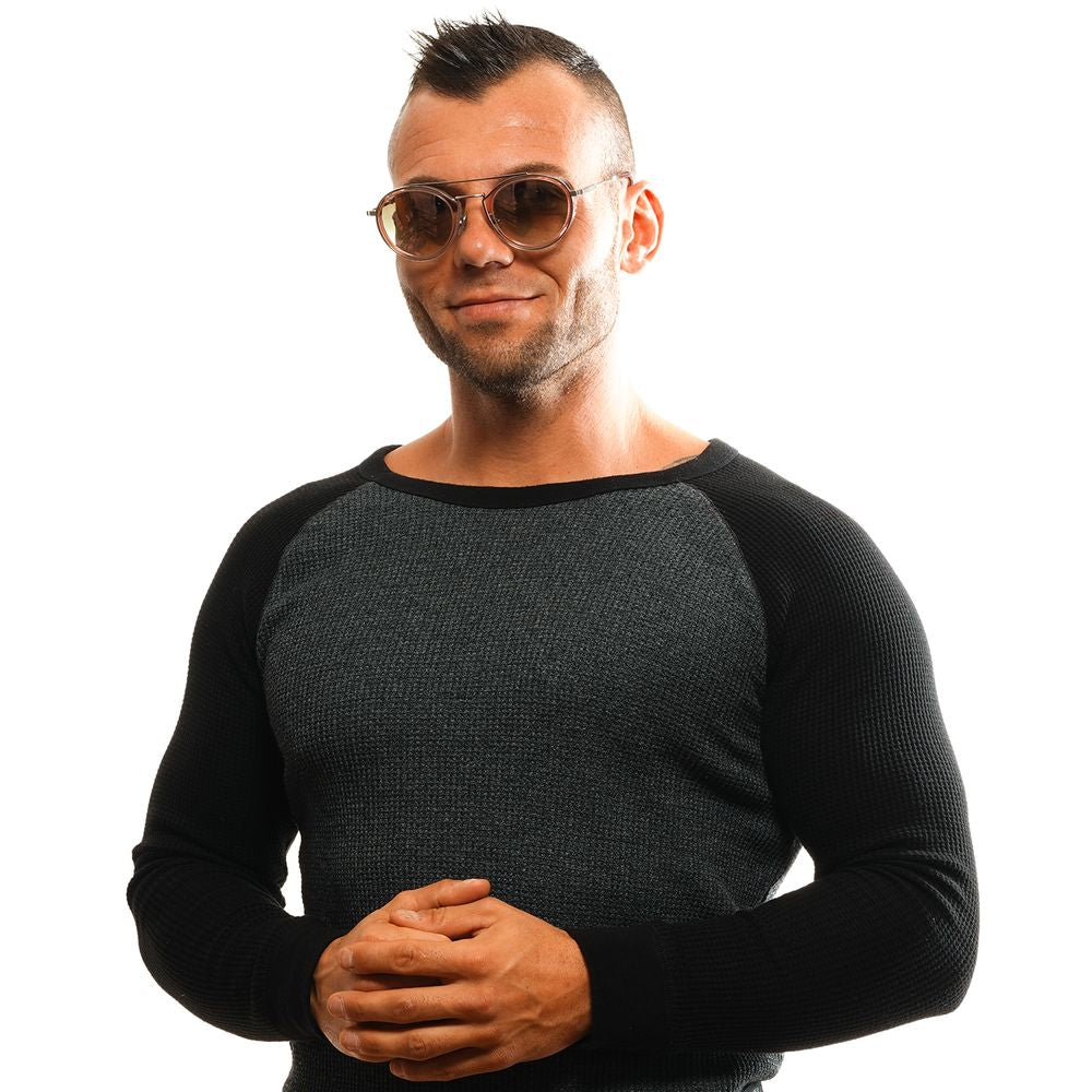 Man wearing Omega Pink aviator sunglasses with mirrored burgundy lenses, black and gray knit sweater, smiling with arms folded.