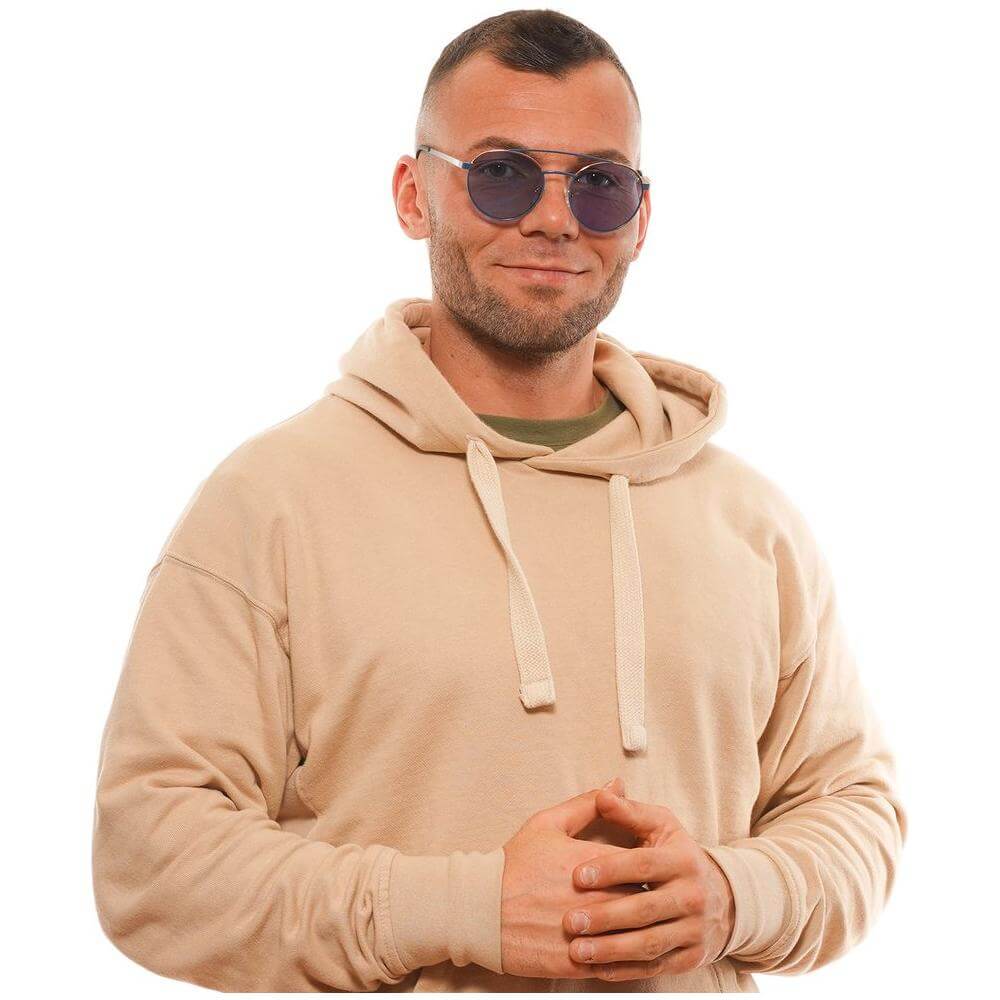 Man wearing Guess blue aviator sunglasses with metal and plastic frame, full-rim style, offering 100% UVA/UVB protection, styled with beige hoodie.