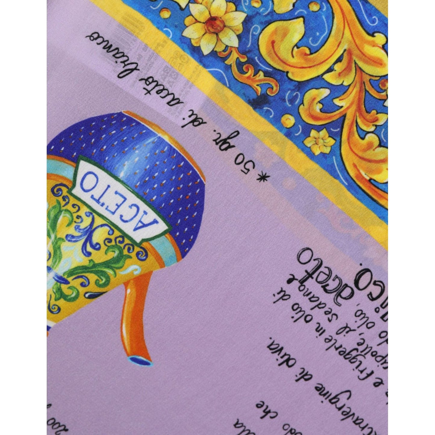 Close-up of Dolce & Gabbana purple silk fabric with vibrant Siciliana Caponata print, featuring blue and gold decorative motifs.