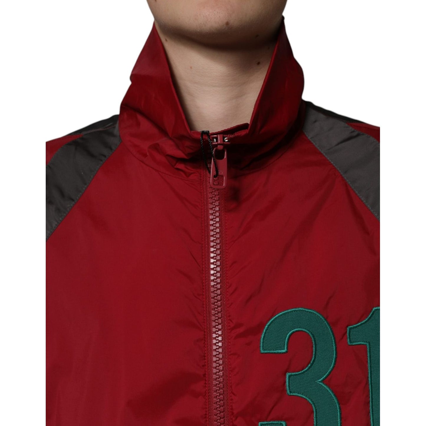 Close-up of multicolor windbreaker jacket with turtleneck and full zip, featuring logo detail on red fabric.