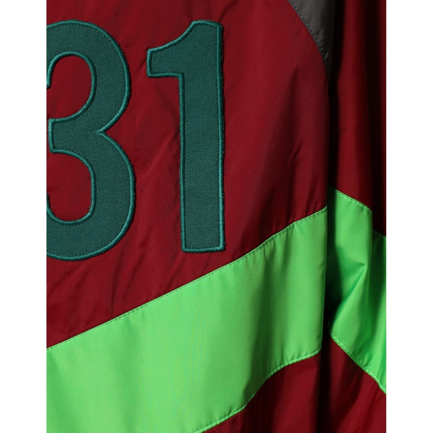 Close-up of Dolce & Gabbana multicolor windbreaker featuring red, black, green "31" design, showcasing sporty style and luxury fashion.