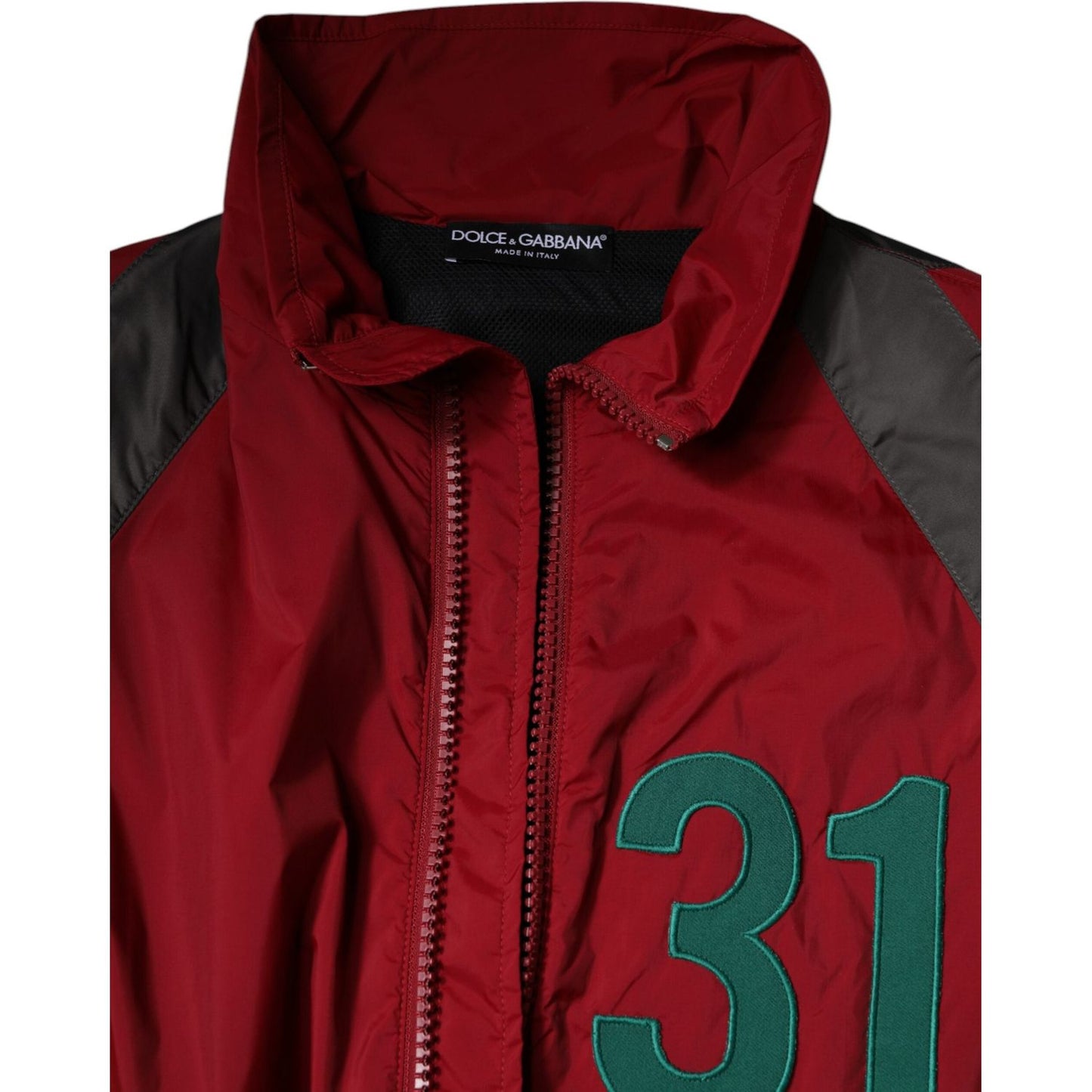 Dolce & Gabbana red nylon windbreaker with green number detail, turtleneck, and full zipper. Brand logo visible. Made in Italy.