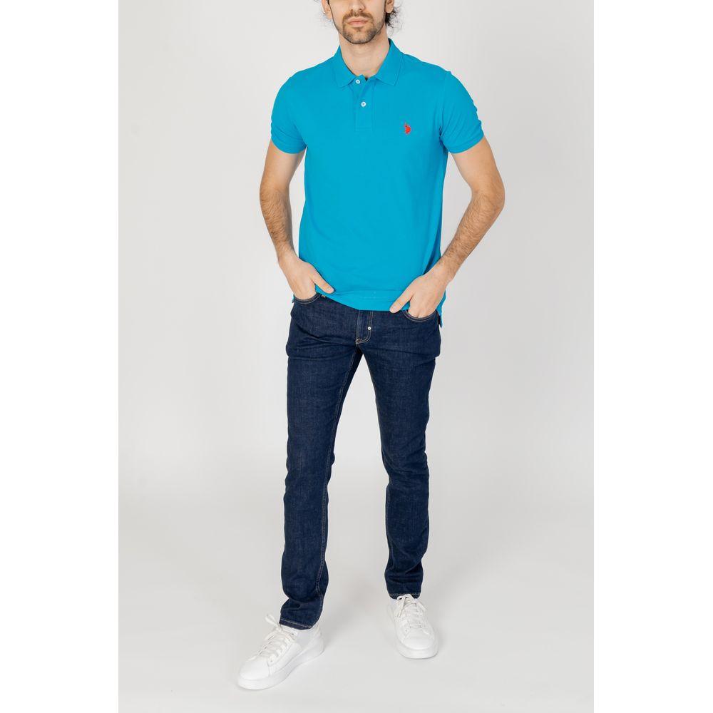 Man wearing a U.S. Polo Assn. blue cotton polo shirt with embroidered logo, paired with dark jeans and white sneakers, full front view.