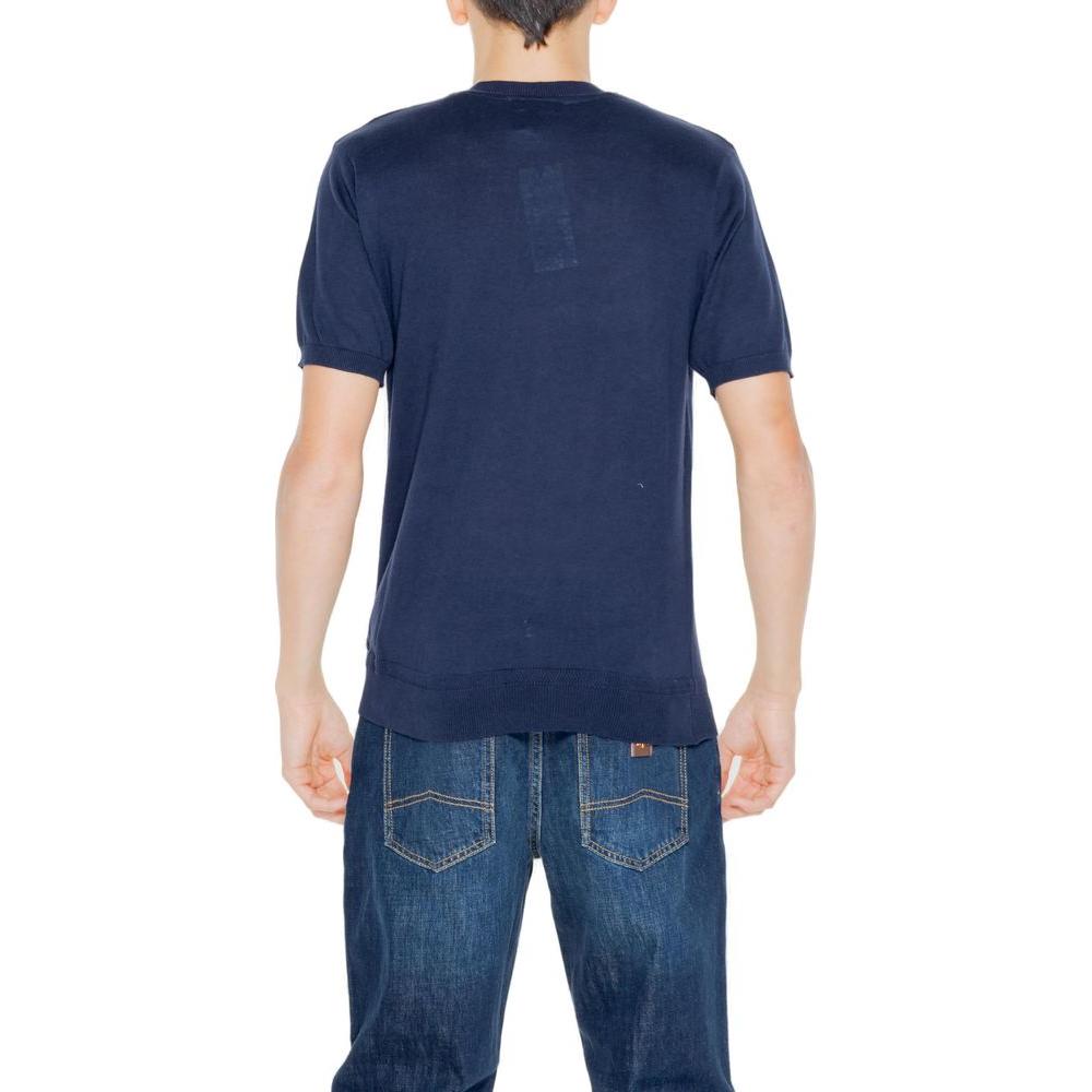 Back view of a man wearing a Hamaki-Ho blue cotton short sleeve t-shirt, part of the Spring/Summer collection, paired with denim jeans.