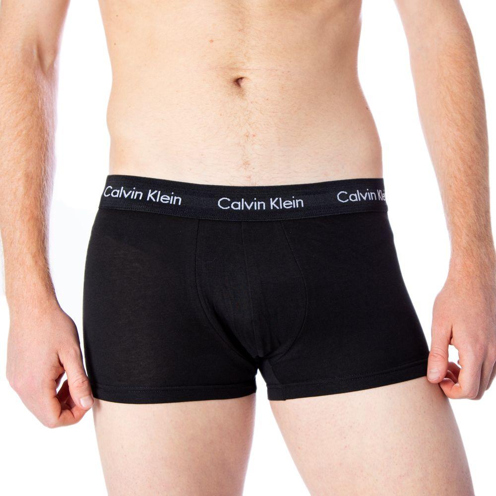 Man wearing Calvin Klein black cotton boxer briefs with logo waistband, showcasing fit and style.