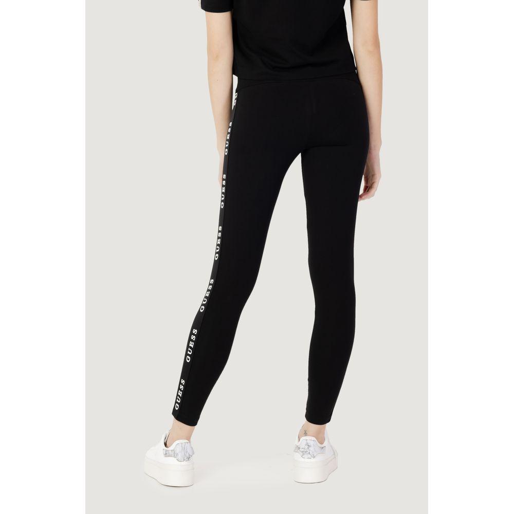 Woman wearing Guess Active black high-waisted leggings with logo, made of cotton, polyester, and elastane for sports activities.