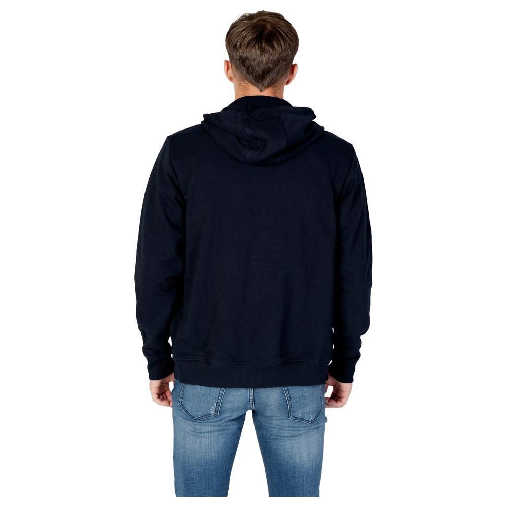 Back view of model wearing men's Tommy Hilfiger blue organic cotton hoodie jeans, recycled materials, fall winter collection.