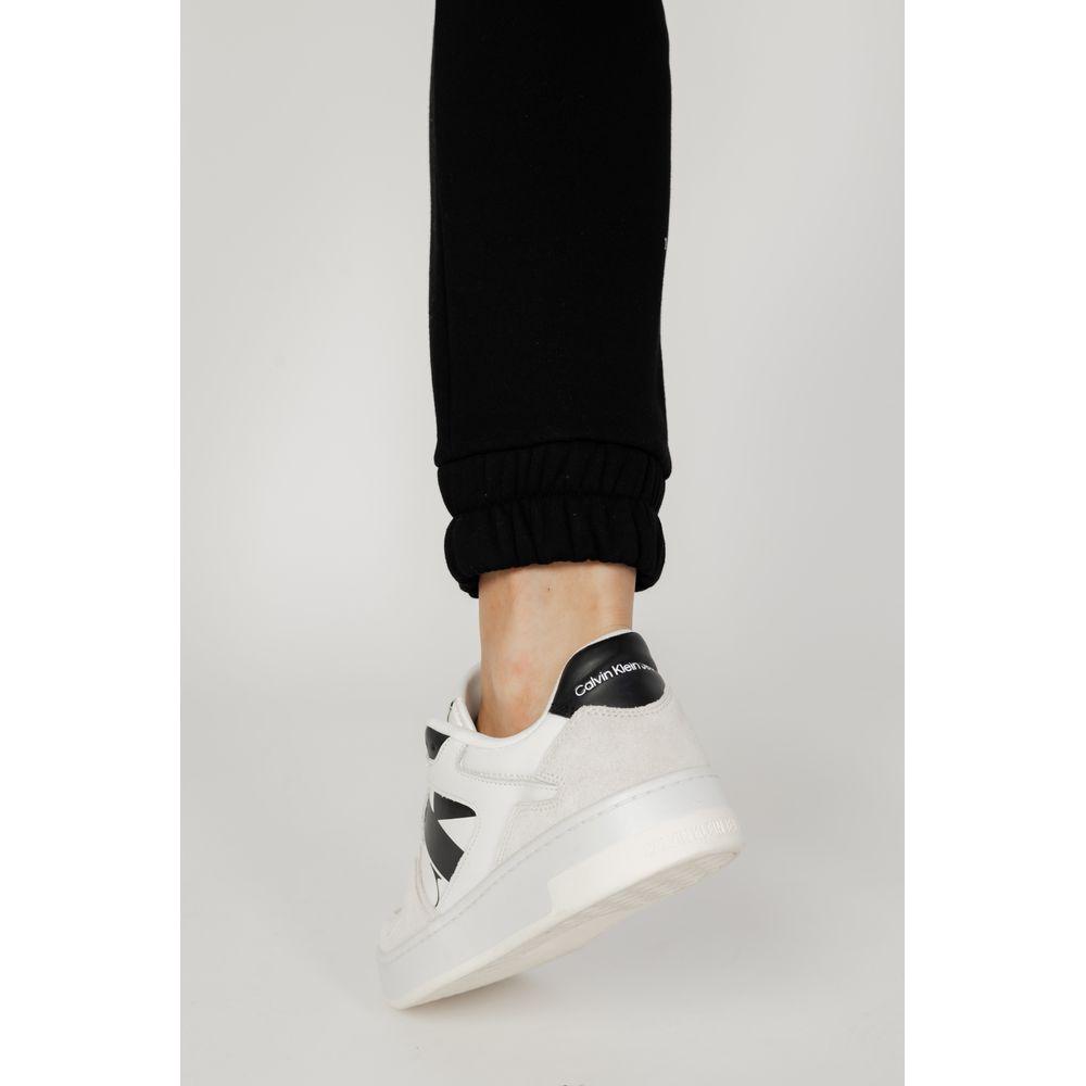 Close-up of a woman's leg in a Blauer black cotton jean and pant, paired with white sneakers, showcasing the autumn/winter collection.