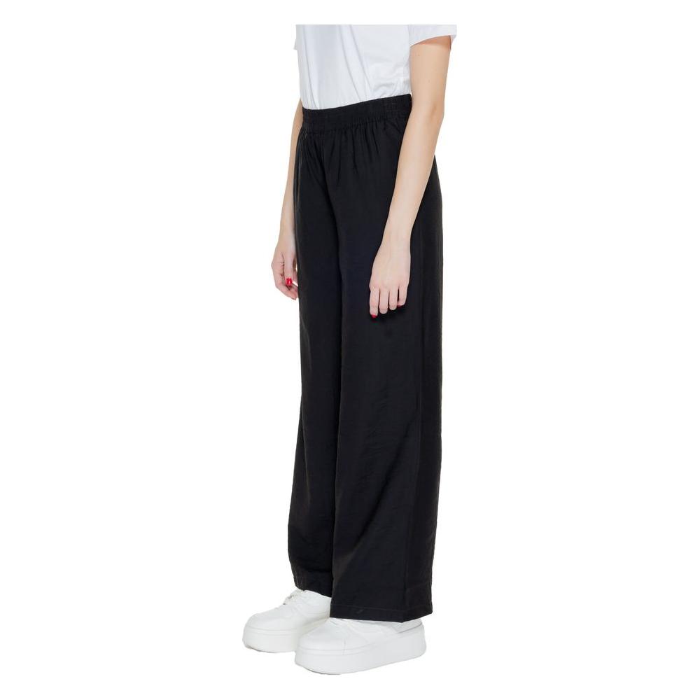 Woman wearing black viscose palazzo trousers, Jacqueline De Yong Spring Summer collection, side view, white sneakers.