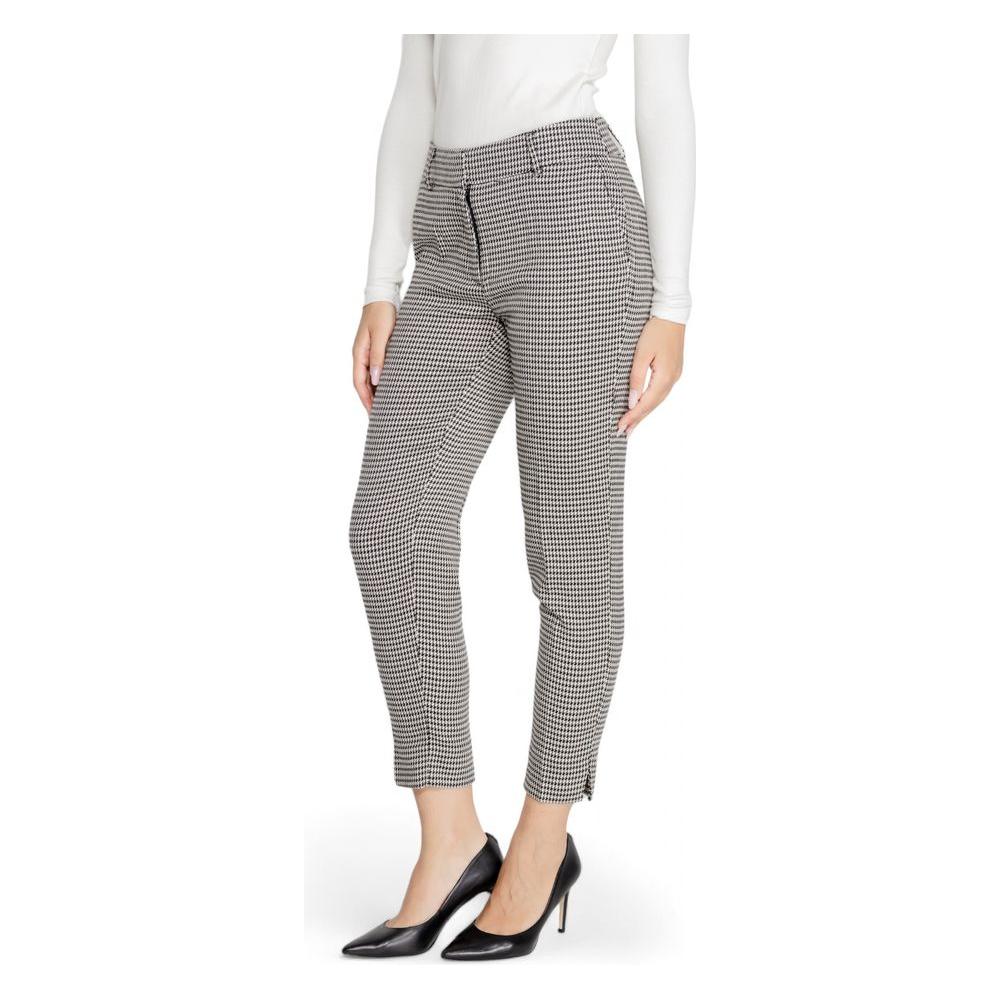 Woman wearing black and white checkered polyester pants from Fall/Winter collection, paired with a white top and black heels.