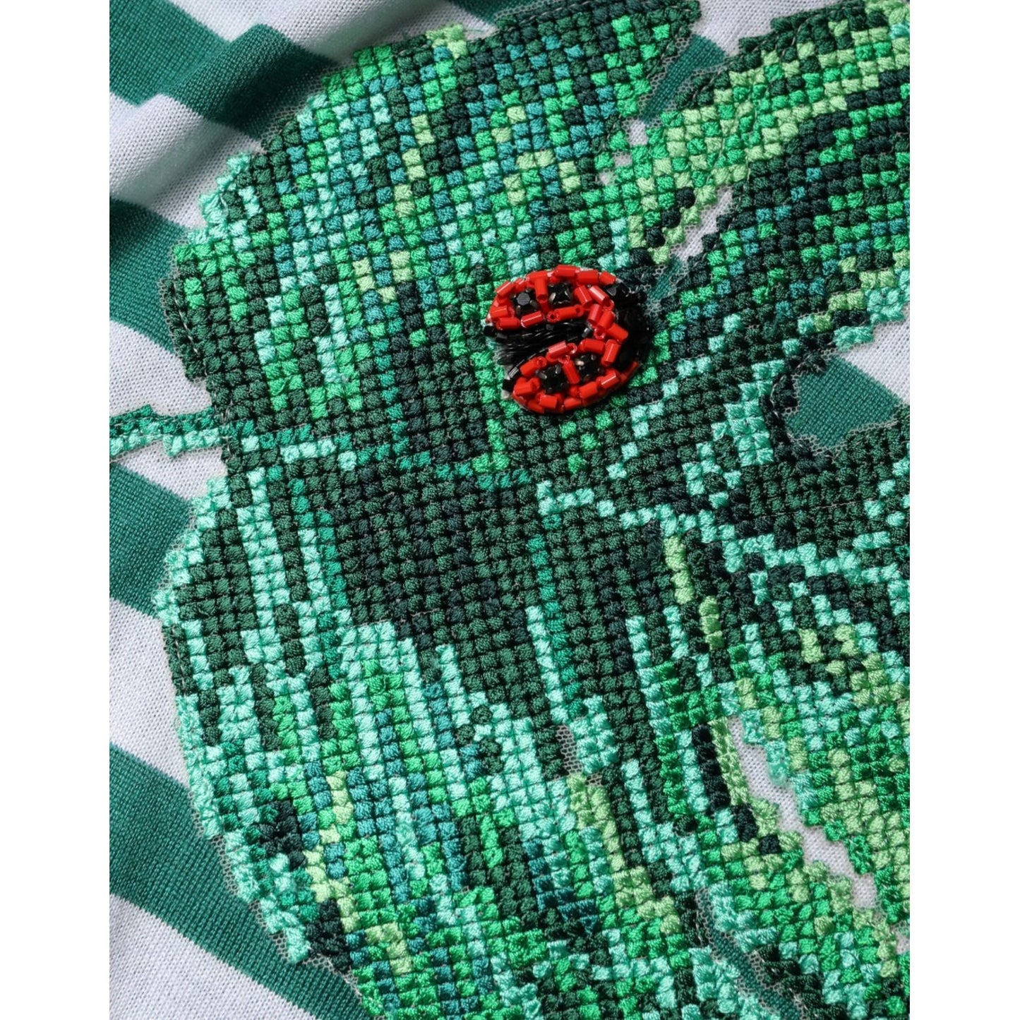 Embroidery detail of Dolce & Gabbana T-shirt with green leaf and stripes, crafted from cashmere and silk.
