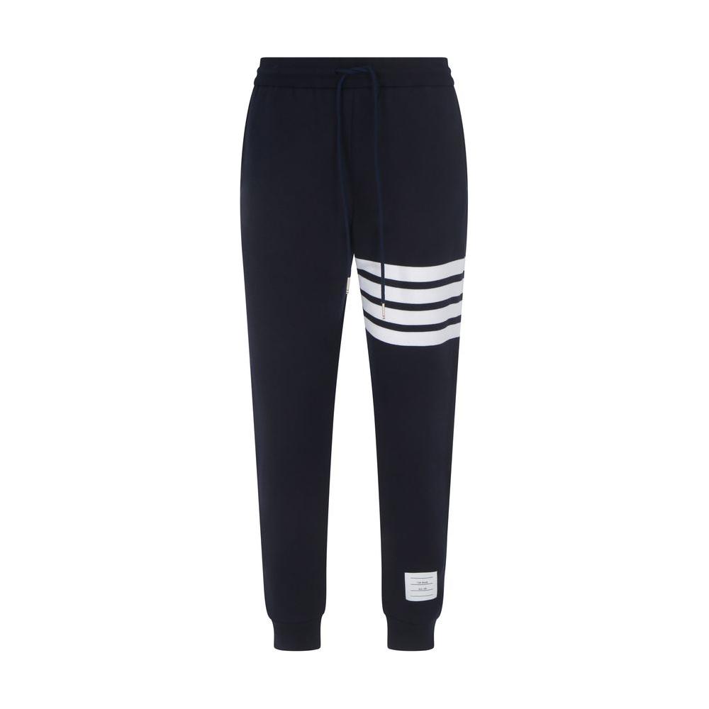 Thom Browne cotton sweatpants with elastic waistband, drawstring, and iconic white bands on left leg, jogger style, brand patch on back.
