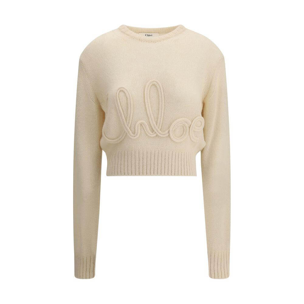 Chloé alpaca sweater in cream with ribbed crew neck, hem, and cuffs, featuring iconic stitched branding on the front. Cropped youthful style.