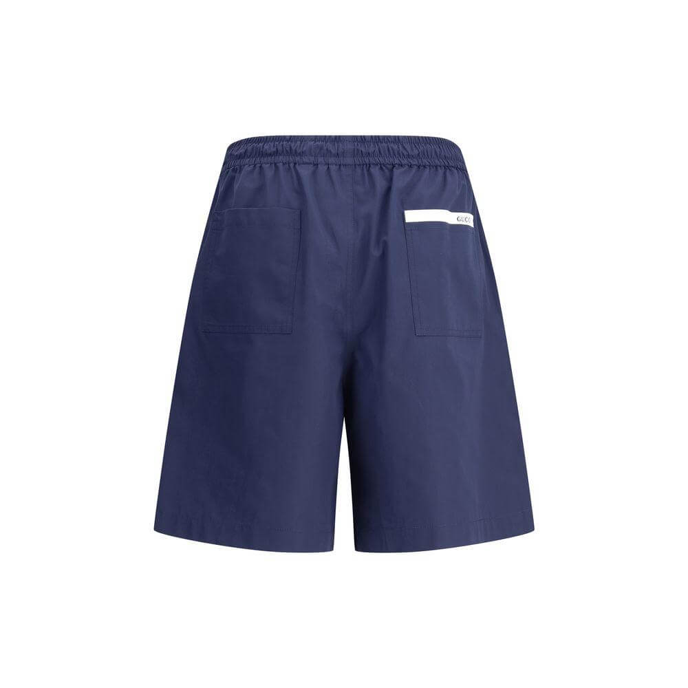 Navy blue Gucci shorts with elastic waistband, adjustable drawstring, logoed back patch pocket. Stylish and comfortable design.