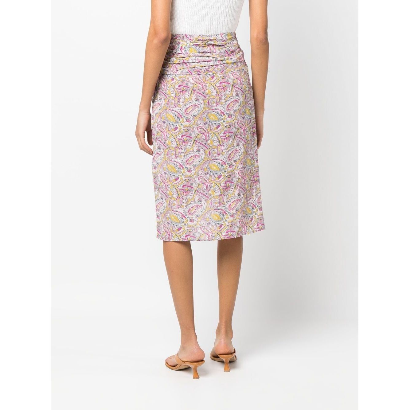 Back view of a model wearing an IRO beige knee-length skirt with an all-over pink graphic print, draped detailing, and a high waist.