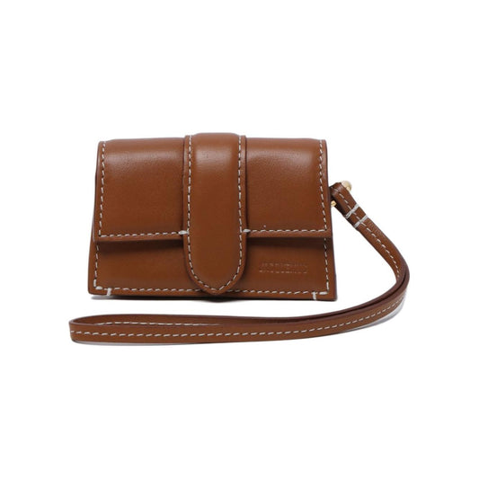 Jacquemus The Bambino flap case in light brown leather with white stitching, debossed logo, and wrist strap. AirPods compatible pouch.