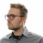 Man wearing Police Gray Men Glasses Frame, full-rim style, with metal and plastic material, in a grey shirt.