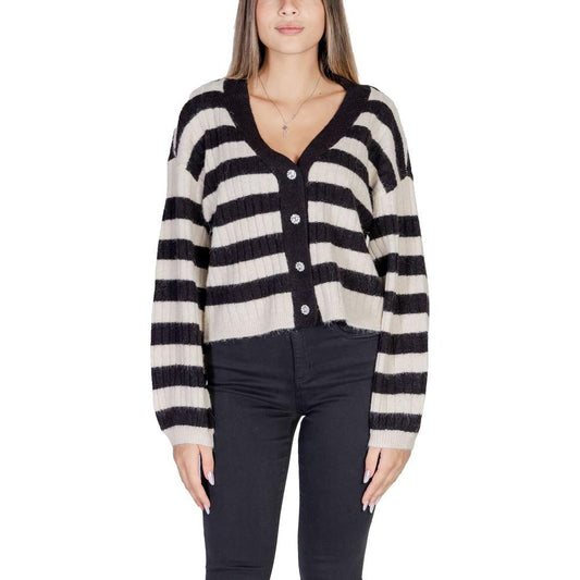 Woman wearing black and white striped cardigan with buttons, paired with black pants, showcasing stylish women's knitwear fashion.