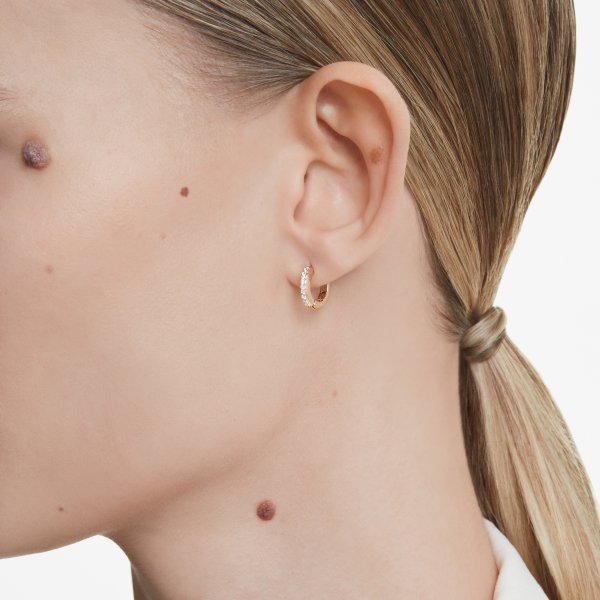 Woman wearing SWAROVSKI Mod. 5690669 silver earrings, showcasing elegant design with quartz analog movement and 5 ATM water resistance.