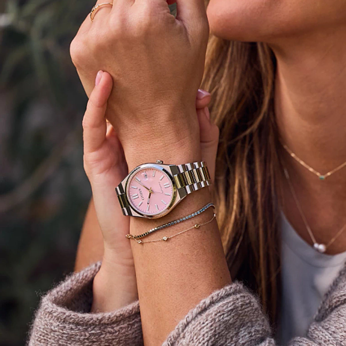 CITIZEN MOD. NJ0200-50Z wristwatch with pink dial on woman's wrist, showcasing stylish accessories and elegance.