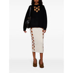 Fashion model wearing black sweater, cream cutout skirt, and carrying Chloé Small Bracelet Hobo Bag.
