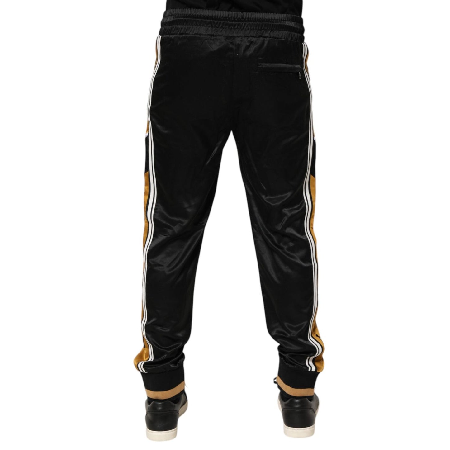 Back view of Dolce & Gabbana Black Gold Satin Crown Side Stripe Jogger Pants with crown embroidery and ribbed cuffs.