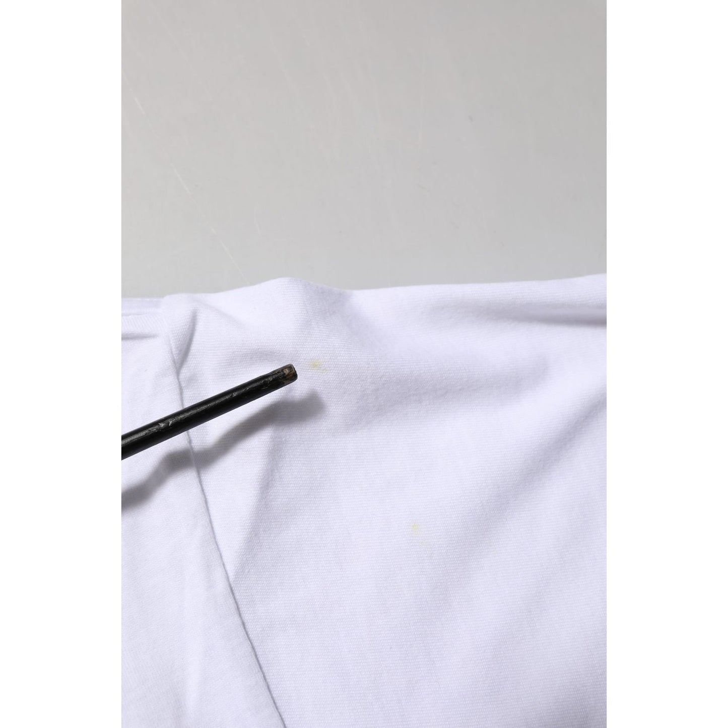 Close-up of defect on Dolce & Gabbana White Graphic Print Cotton CrewNeck T-shirt showing minor stain on fabric.
