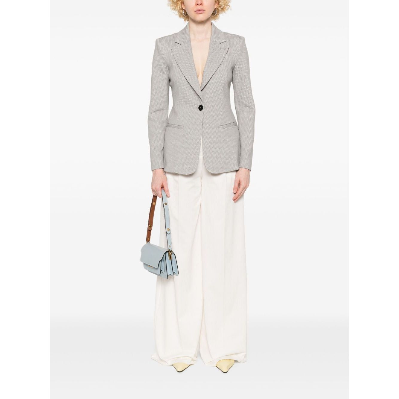 Model wearing Emporio Armani Icon Blazer in light grey with front button fastening and side welt pockets, styled with wide-leg trousers.