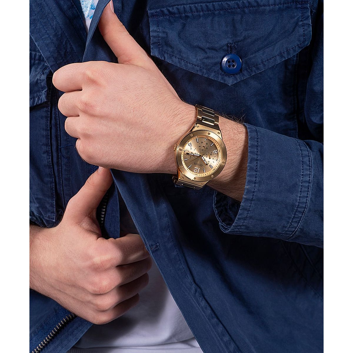 Gent wearing GUESS Mod. GW0454G2 watch with quartz analog movement and water resistance up to 5 ATM, featuring a gold design.