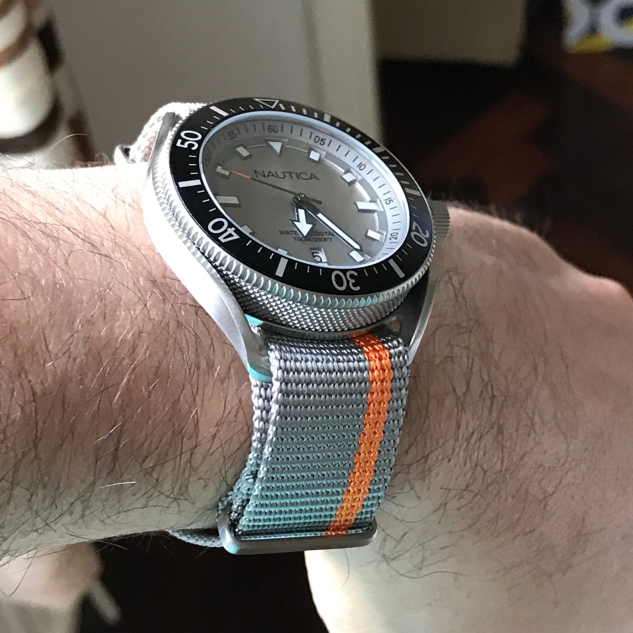 NAUTICA Mod. NAPPRF003 on wrist, quartz analog gent's watch, 45mm mineral dial, 10 ATM water resistant, with gray and orange nylon strap.