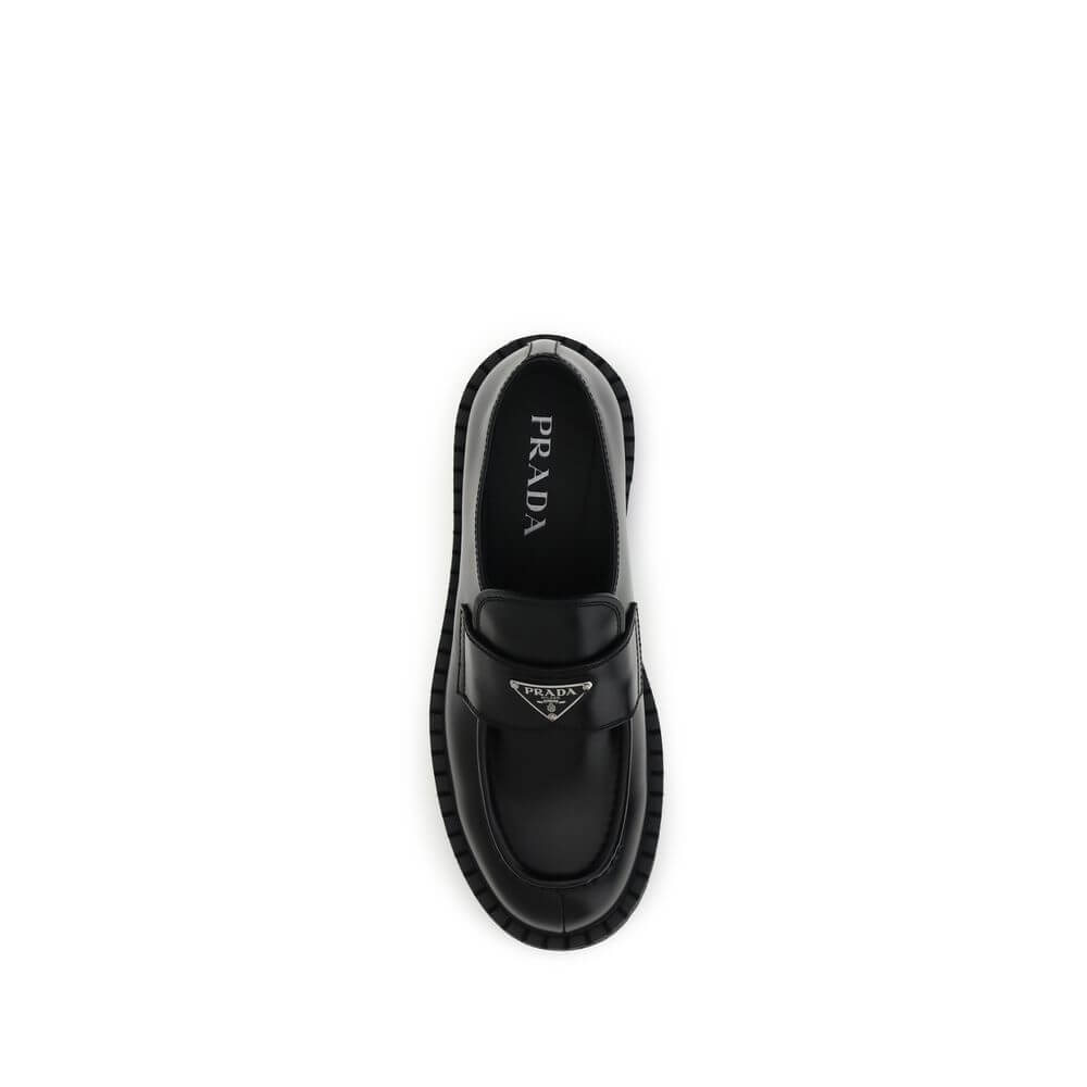 Prada Black Calf Leather Bos Taurus Slip-On Loafers with enameled triangle, stitched tray, and rubber sole.