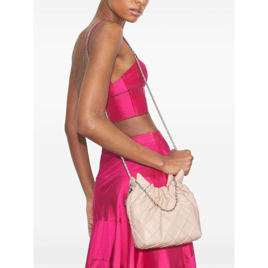 Woman holding Tory Burch Fleming mini leather hobo bag in pale pink with quilted design and chain-link strap