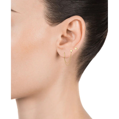 Elegant gold chain earrings on a woman's ear, showcasing minimalist heart designs.