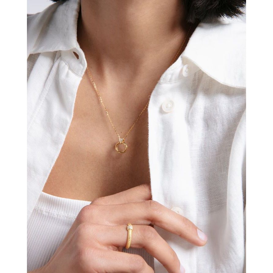 Woman wearing a gold necklace and ring with a white shirt
