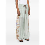 Woman wearing Zimmermann Coco trousers featuring a sage green floral print with elasticated drawstring waistband and side pockets.