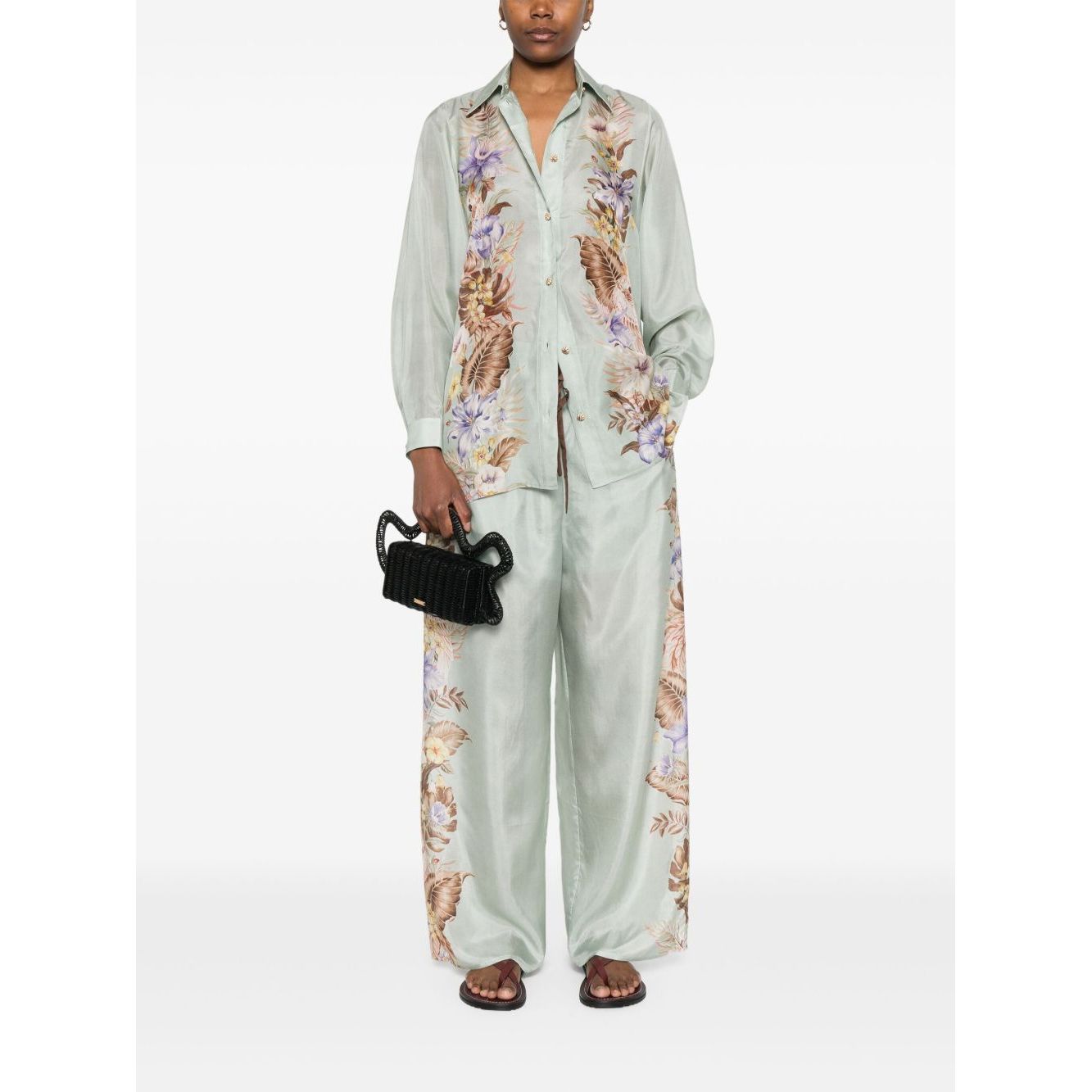 Woman wearing Zimmermann Coco trousers in sage green with floral print, standing with hands in pockets, front view showing elasticated waistband.