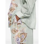 Model wearing Zimmermann Coco trousers in sage green with floral print and elasticated waistband.